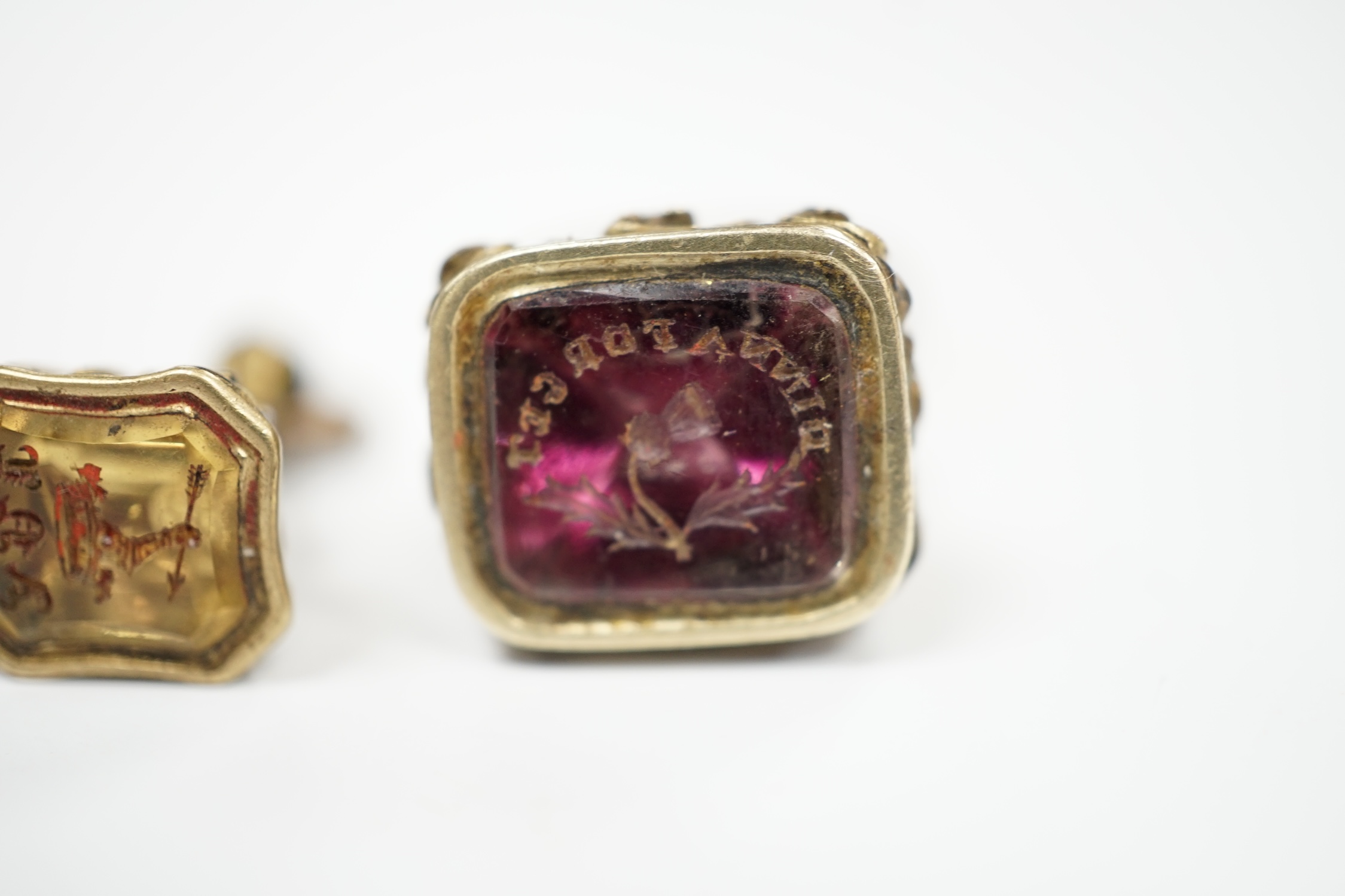 Two 19th century yellow metal overlaid and gem set fob seals, the largest with matrix carved with thistle and motto, 25mm.